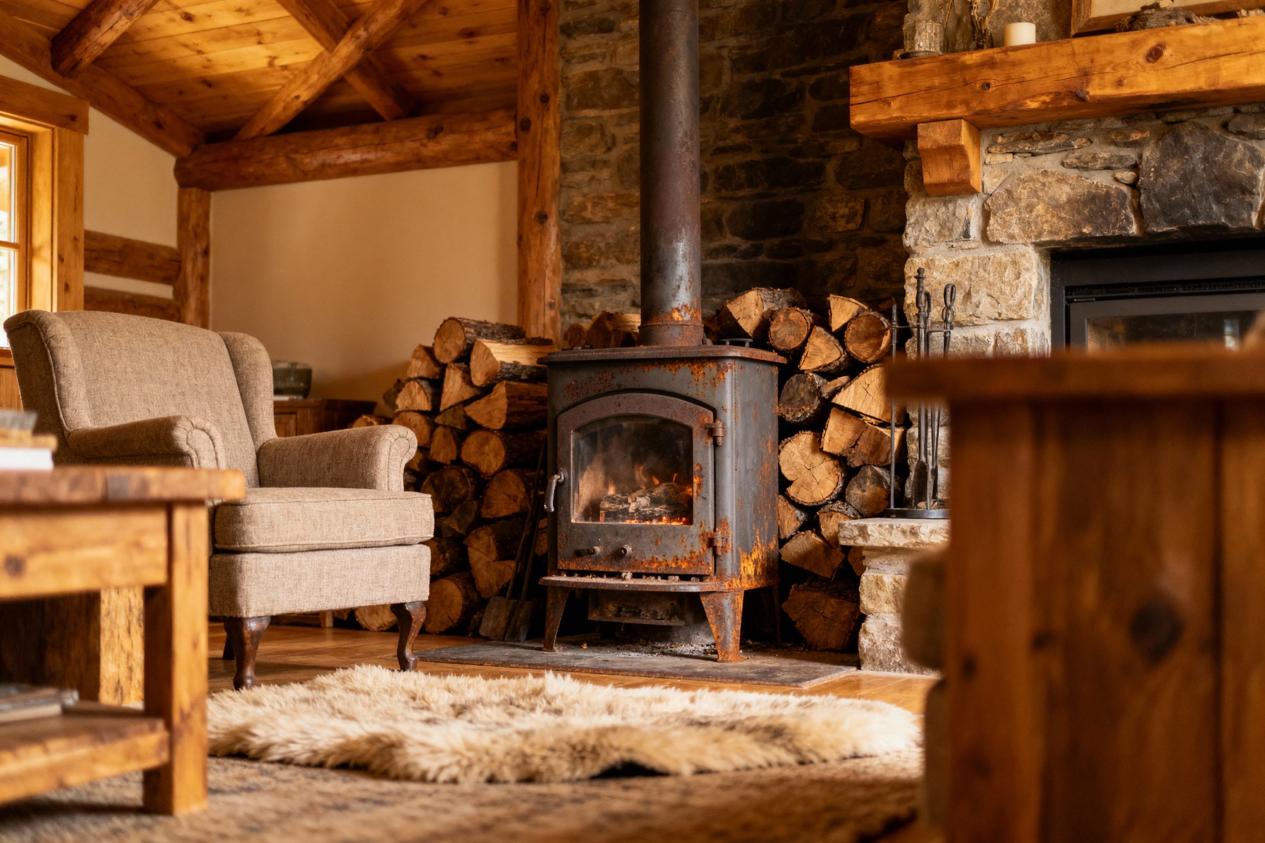 pexels-michal-pech-213601-757318 (1) Intérieur chaleureux d'une maison avec un poêle à bois, des bûches empilées, un fauteuil et un tapis en fourrure.