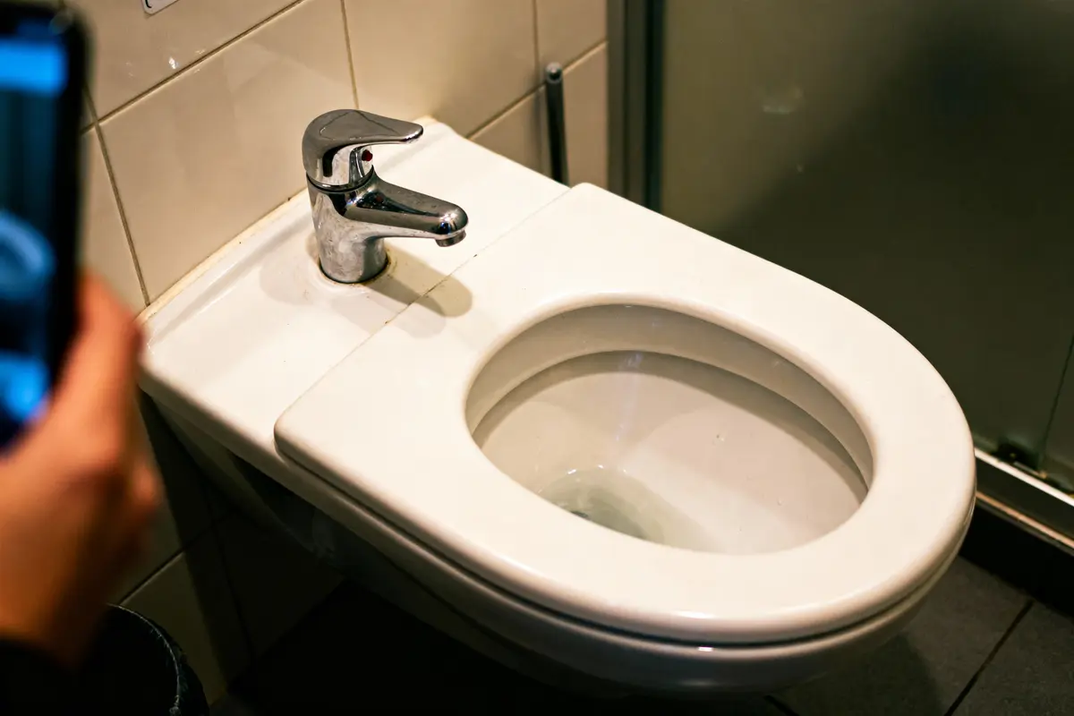Bidet blanc avec robinet en chrome dans une salle de bains carrelée.