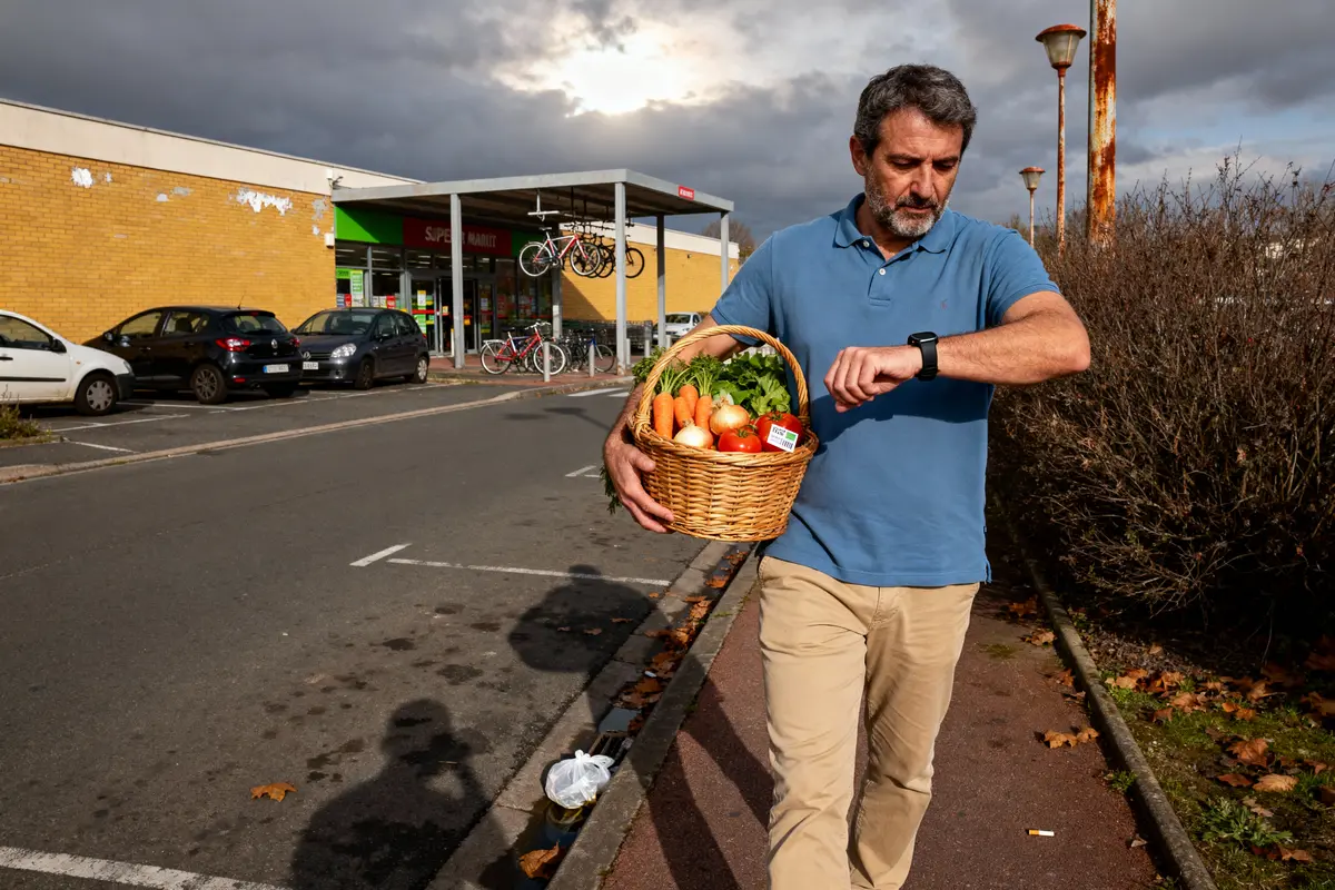 pexels-michal-pech-213601-757318 (1) Un homme portant un panier de légumes regarde sa montre devant un supermarché avec des vélos.