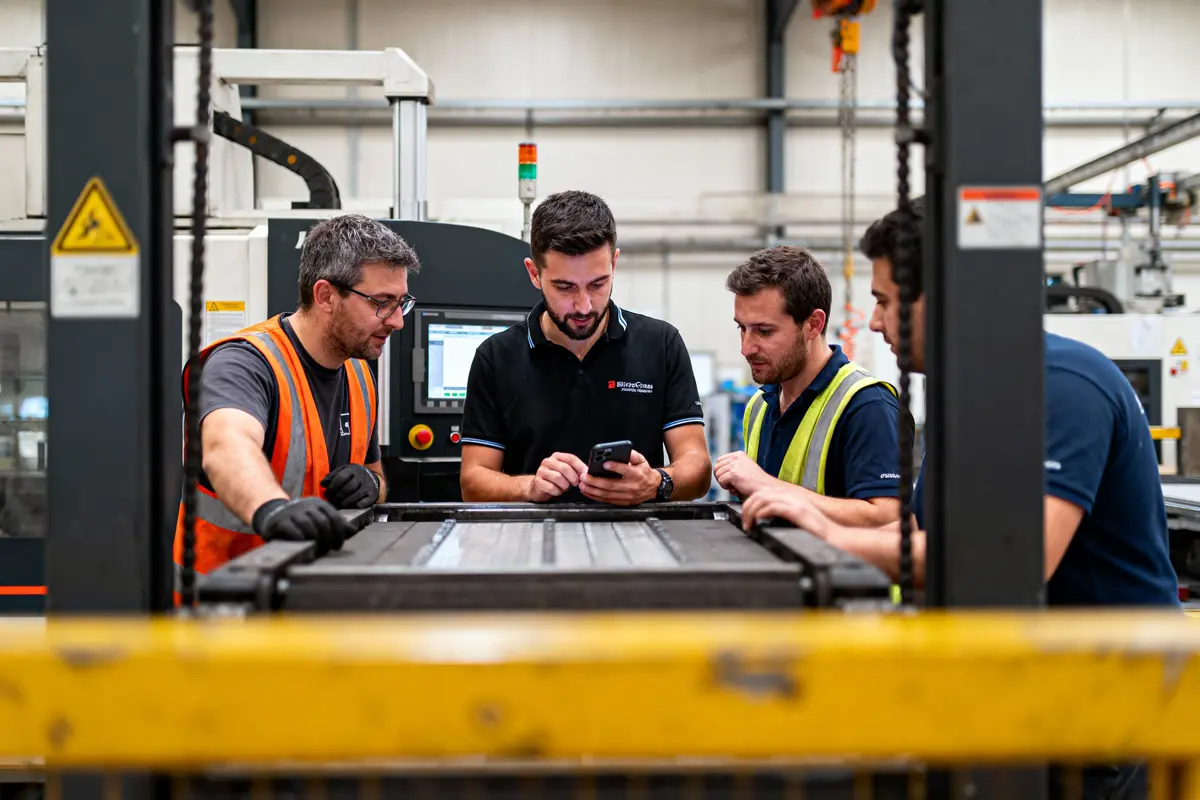 pexels-michal-pech-213601-757318 (1) Quatre hommes en gilets de sécurité travaillent ensemble dans une usine, consultant un smartphone.