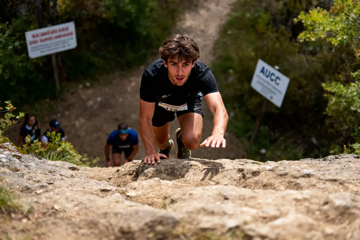 pexels-michal-pech-213601-757318 (1) Homme grimpant un sentier rocheux lors d'une course, sous le regard d'autres participants en arrière-plan.